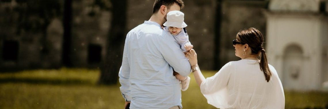 a man holding a baby while standing next to a woman